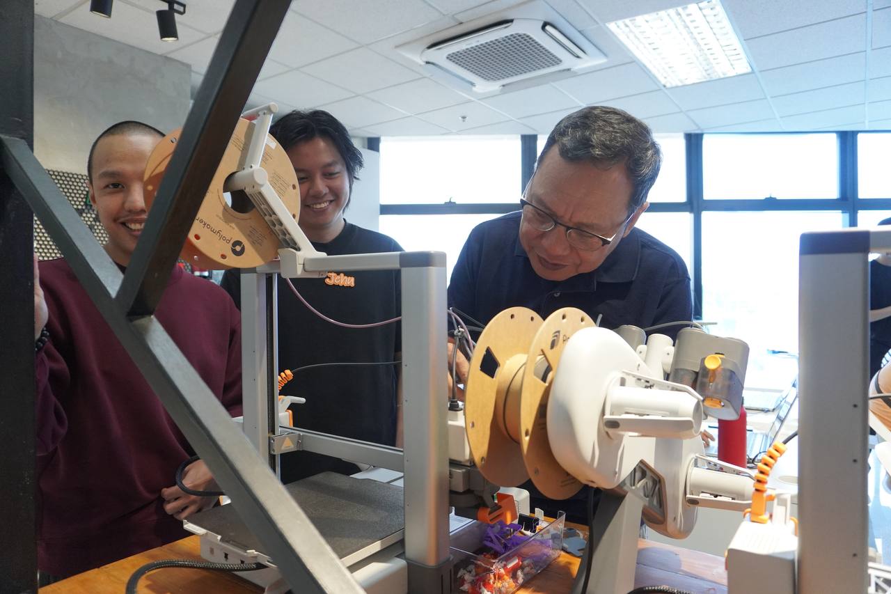 Workshop participants smiling with a 3D printer